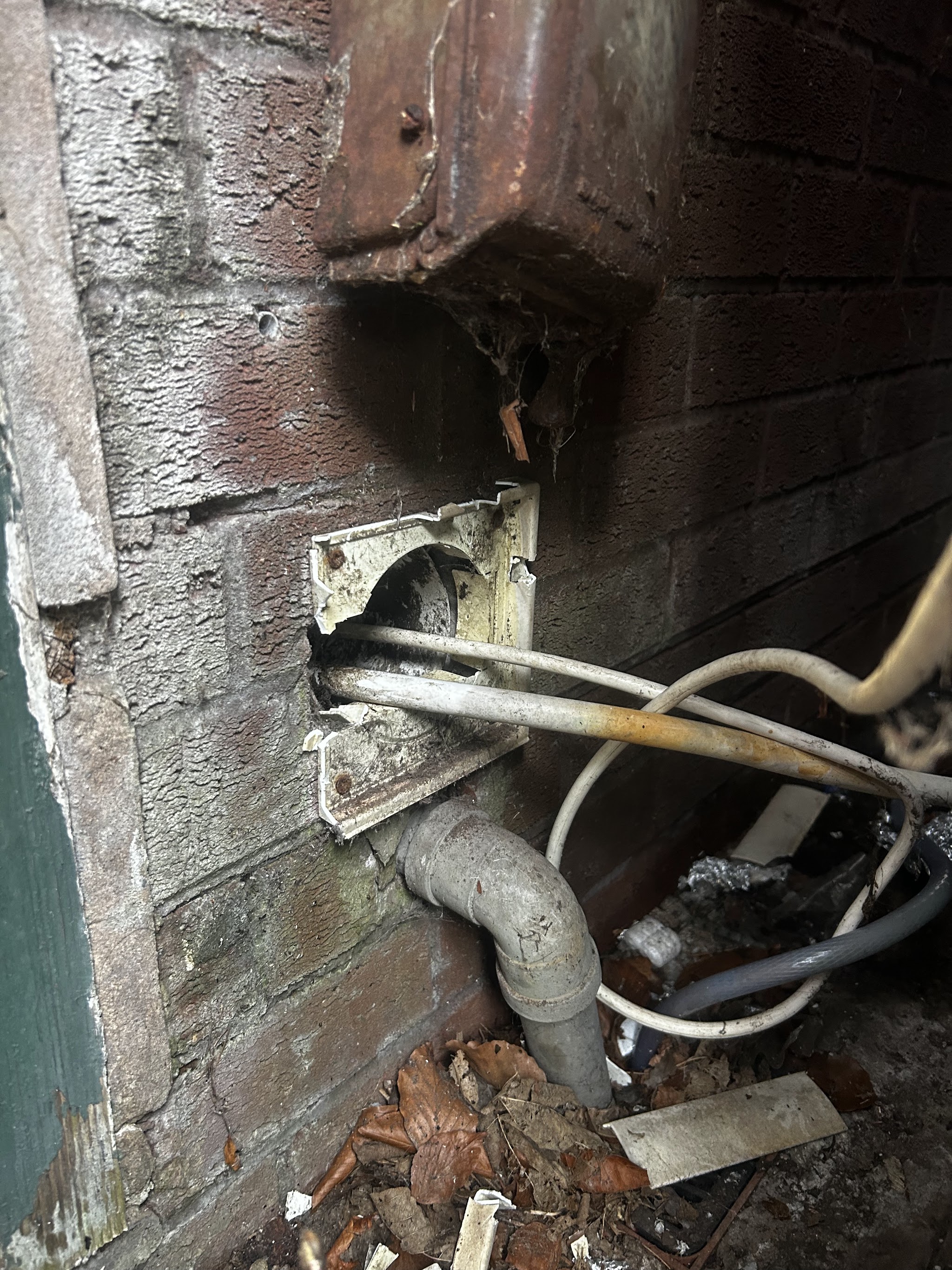 Cables running into a brick wall through a broken vent cover